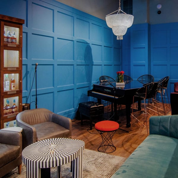 A vibrant blue lounge area with a piano, various seating, and a liquor cabinet.